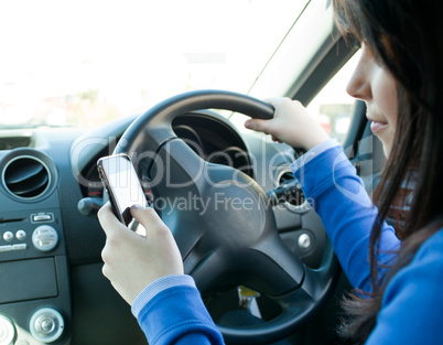 Beautiful brunette woman using her cellphone while driving