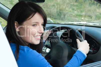 Happy female teenager sitting in her new car