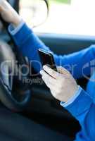 Close-up of a caucasian young woman sending a text while driving