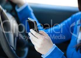 Close-up of a teenager sending a text while driving