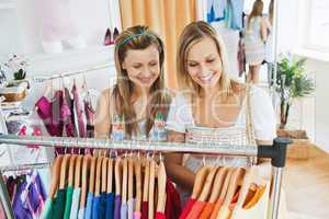 Bright young women choosing colorful shirts together