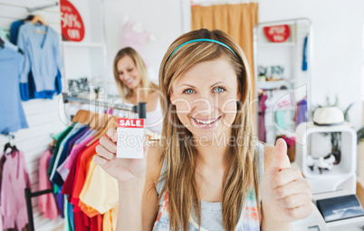 Merry young woman holding a sales paper into the camera with thu