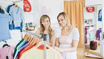 Positive friends choosing colorful clothes in a clothes store