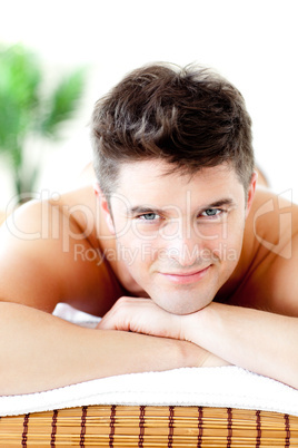 Portrait of a handsome man lying on a massage table smiling at t