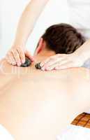 Caucasian young man receiving a back massage with hot stone