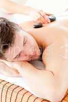 Attractive man enjoying a massage with hot stone