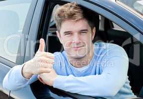 Attractive young man sitting in his car with thumb up