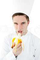 Confident male cook eating a banana