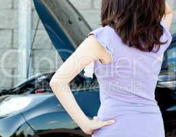 Brunette young woman standing in front of her car