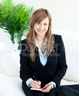 Positive young businesswoman taking notes smiling at the camera