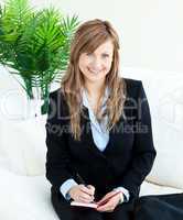 Positive young businesswoman taking notes smiling at the camera