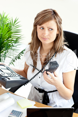 Stressed young businesswoman holding a telephone