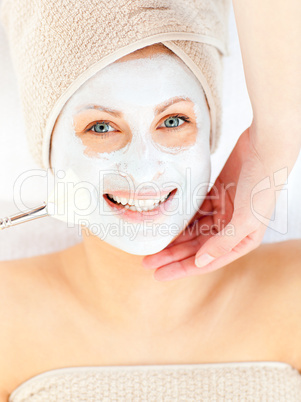 Happy woman with white cream on her face smiling at the camera