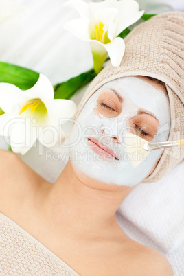 Relaxed woman receiving white cream on her face