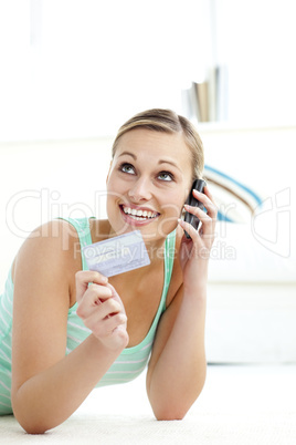Radiant young woman holding a card talking on phone