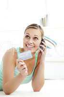 Radiant young woman holding a card talking on phone