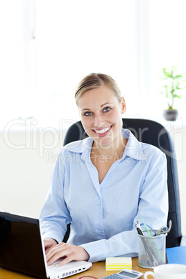 Sophisticated caucasian businesswoman using her laptop smiling a