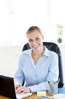 Sophisticated caucasian businesswoman using her laptop smiling a