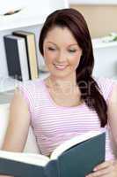 Interested young woman reading a book on the sofa