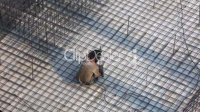 Man welding metal frame for concrete foundation