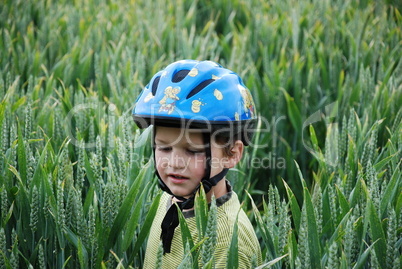 Kind mit Helm im Getreide lernt