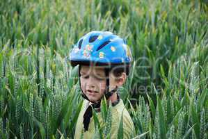 Kind mit Helm im Getreide lernt