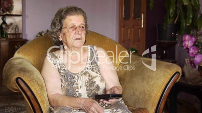 Old retired woman watching television in home