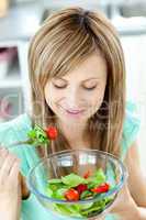 Cute young woman eating a healthy salad in the kitchen