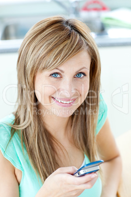 Happy young woman sending a text smiling at the camera