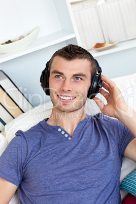 Lively young man listening to music sitting on the couch