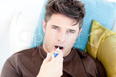 Diseased young man holding a thermometer looking at the camera