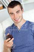 Smiling young man holding a glass of wine looking at the camera