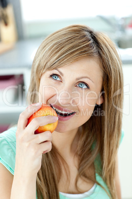 Captivating caucasian woman eating an apple in the kitchen