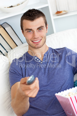 Positive caucasian man holding a remote looking at the camera