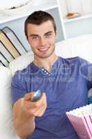 Positive caucasian man holding a remote looking at the camera