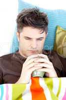 Ill depressed  man holding a cup of coffee lying on the sofa