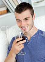 Animated young man drinking wine sitting on the sofa