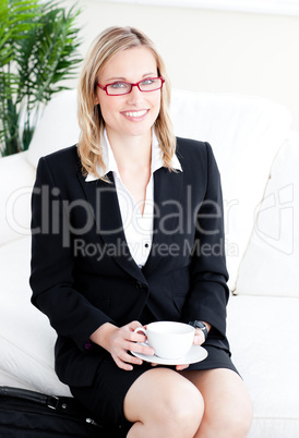 Captivating caucasian businesswoman holding a cup sitting on a s