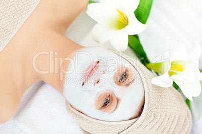 Smiling woman with white cream on her face looking at the camera