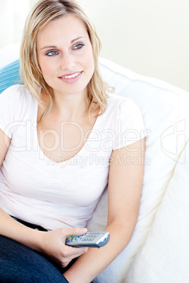Relaxed woman holding a remote sittign on the sofa