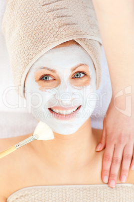 Radiant young woman having white cream on her face