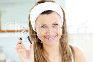Smiling woman holding an eylash curler looking at the camera