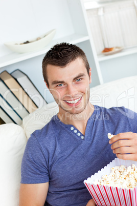 Laughing caucasian man eating popcorn looking at the camera