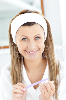 Bright young woman filing her nails smiling at the camera