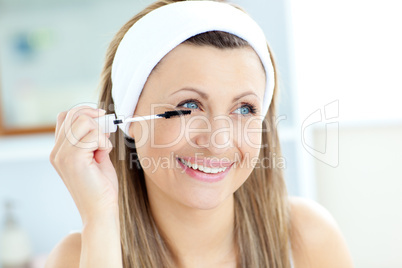 Jolly young woman using mascara in the bathroom
