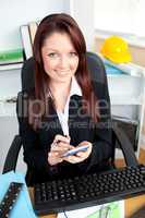 Radiant businesswoman using her calculator looking at the camera