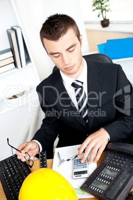 Serious young businessman using his calculator