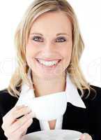 Merry businesswoman holding a cup smiling at the camera