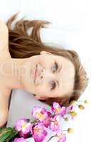 Captivating young woman lying on a massage table with flowers