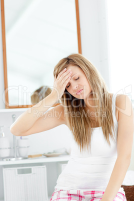 Dejected woman having a headache sitting in the bathroom